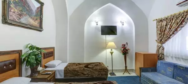 اتاق هتل جهانگردی با تخت، مبل آبی و طاق قوسی