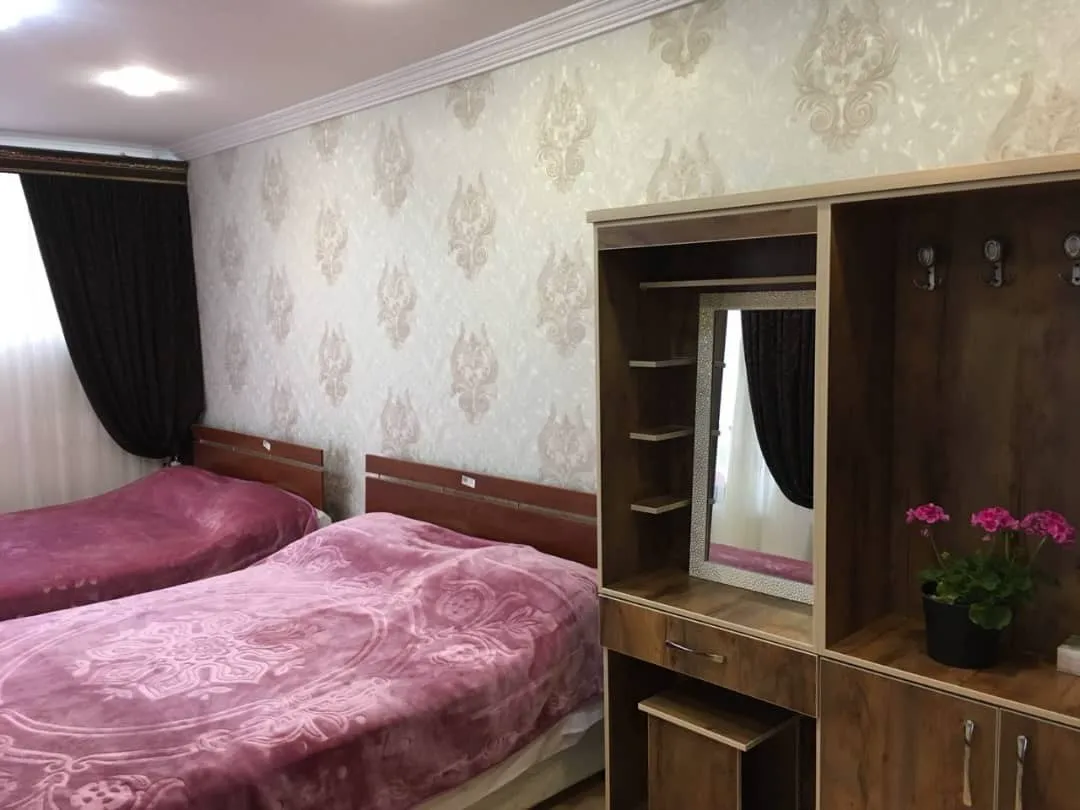 دو تخت و میز آرایش چوبی در اتاق هتل زیارت