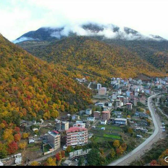 نمای روستای زیارت میان جنگل پاییزی و کوه مه‌آلود