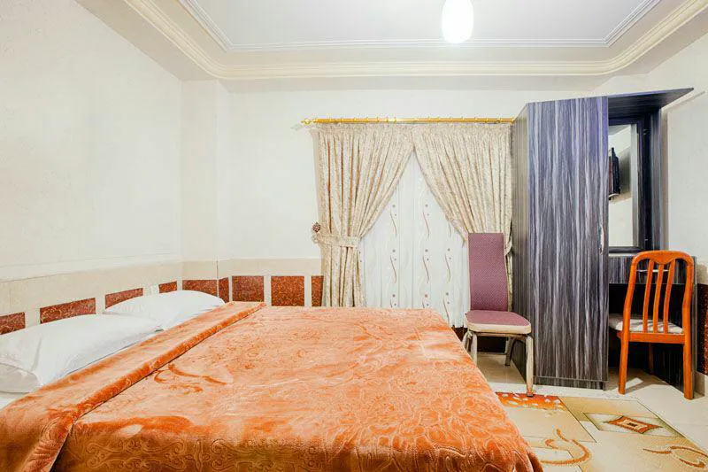 تخت دونفره با روتختی نارنجی در هتل آسماری