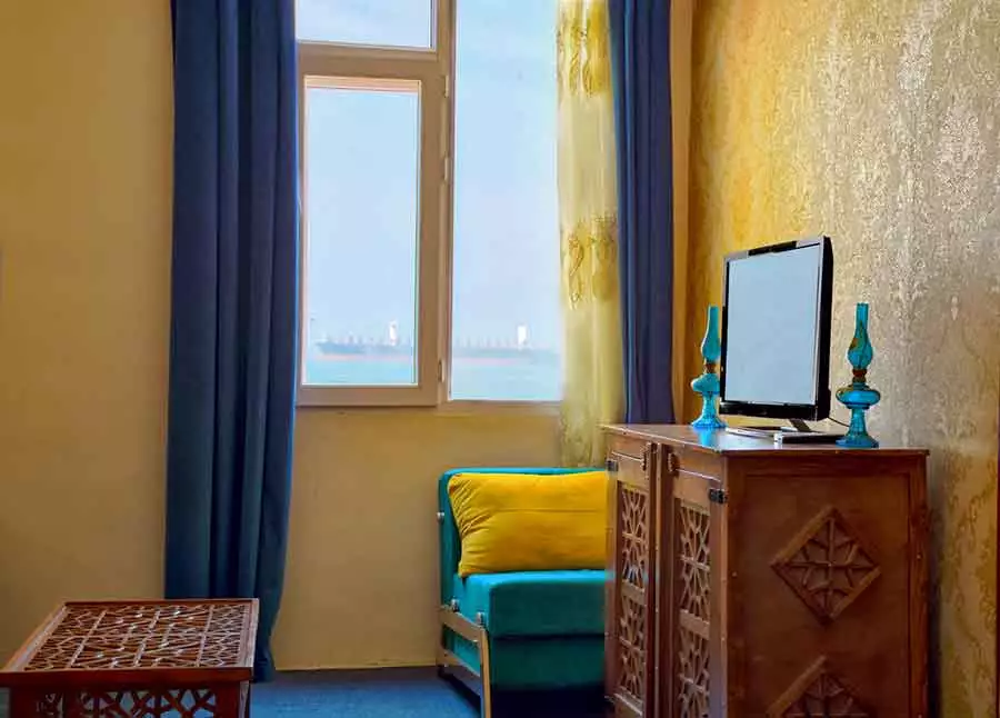 مبل فیروزه‌ای و پنجره اتاق هتل سینگو