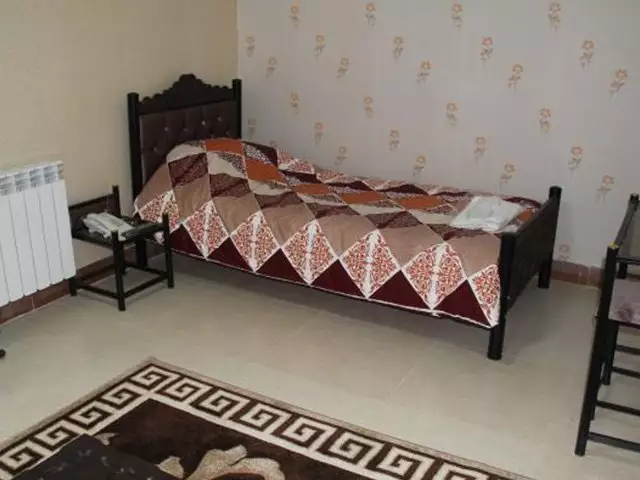 اتاق هتل هالیس با تخت یک‌نفره و روتختی طرح‌دار