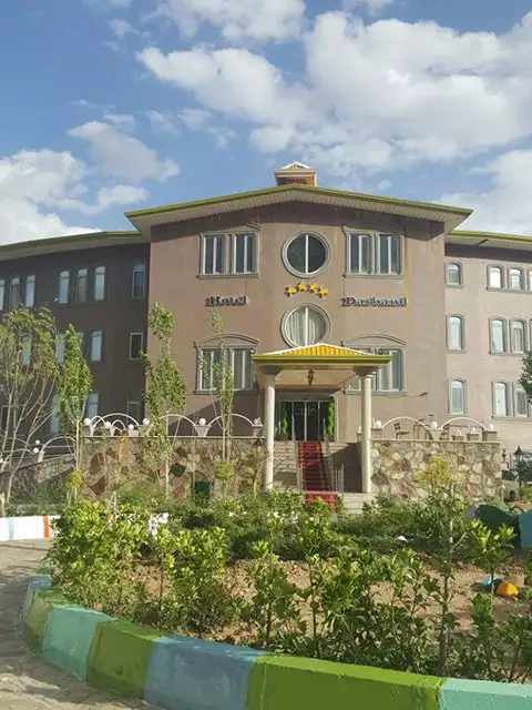 نمای بیرونی هتل دربند میان باغچه و آسمان ابری