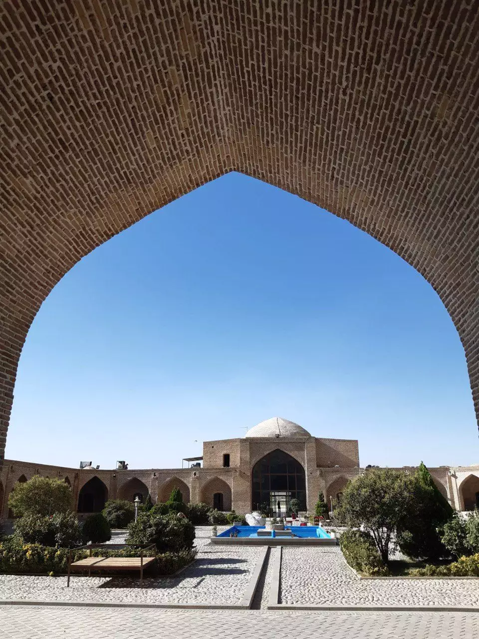 حیاط لاله بیستون با حوض و نمای طاقدار