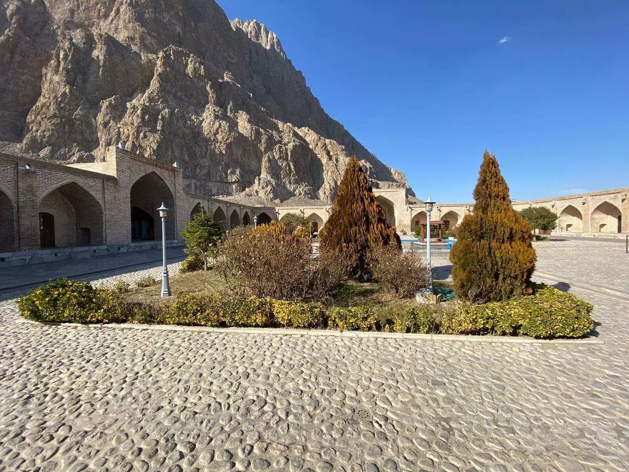 حیاط سنگفرش لاله بیستون در پای کوه