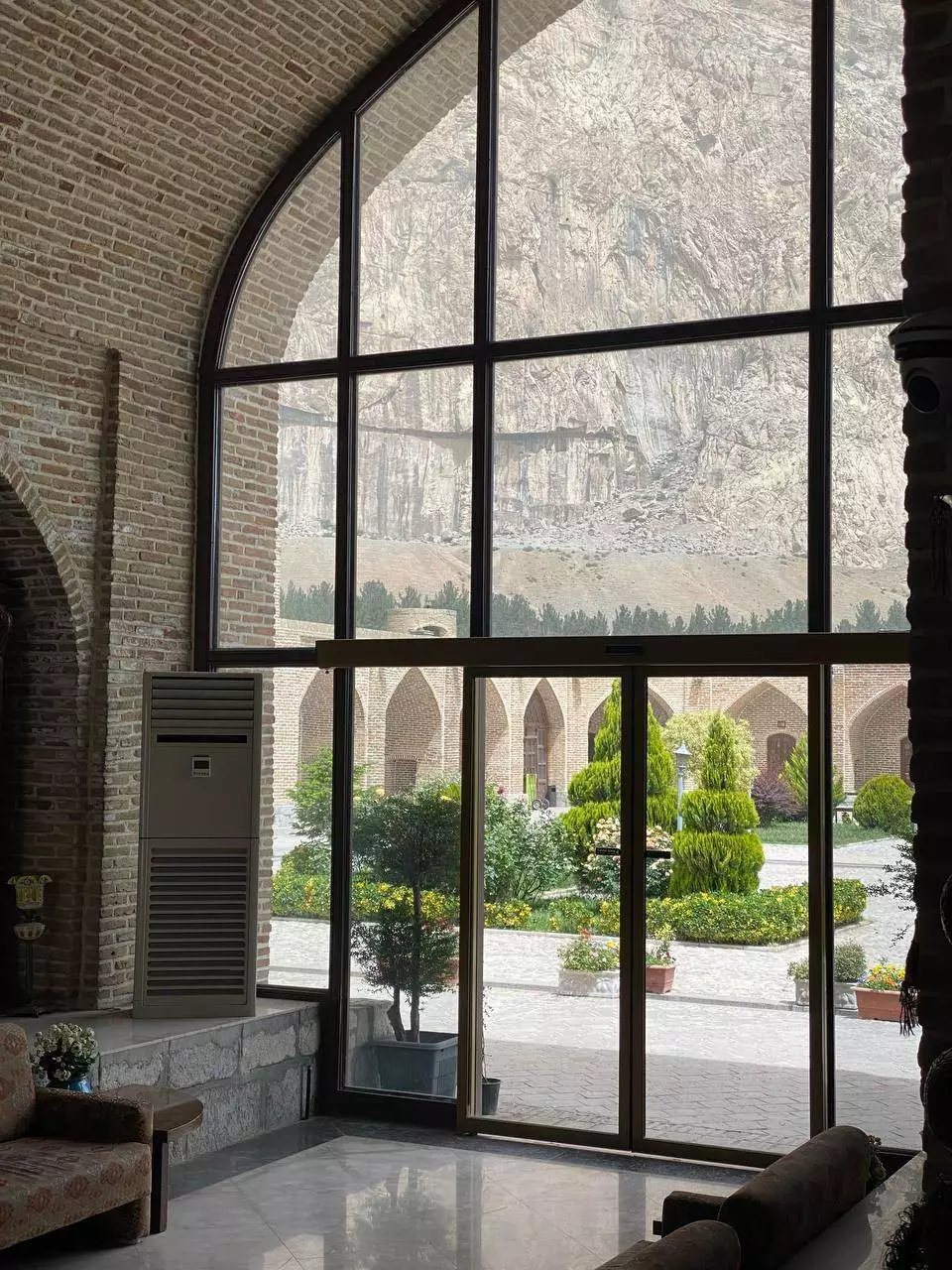 لابی هتل لاله بیستون با پنجرههای بلند رو به باغ