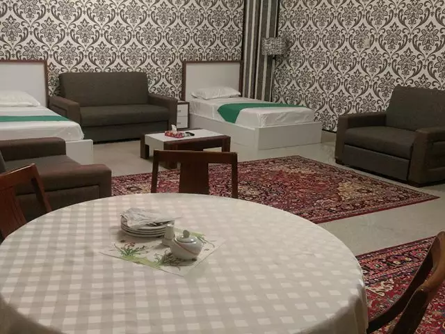 اتاق هتل بزرگ با دو تخت، مبل و فرش ایرانی