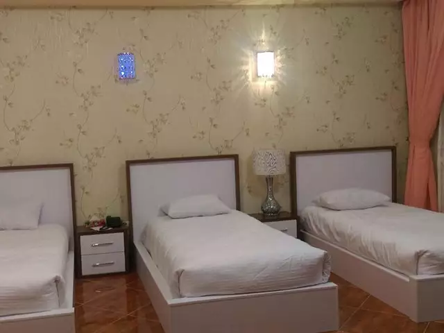 سه تخت یک‌نفره در اتاق هتل بزرگ