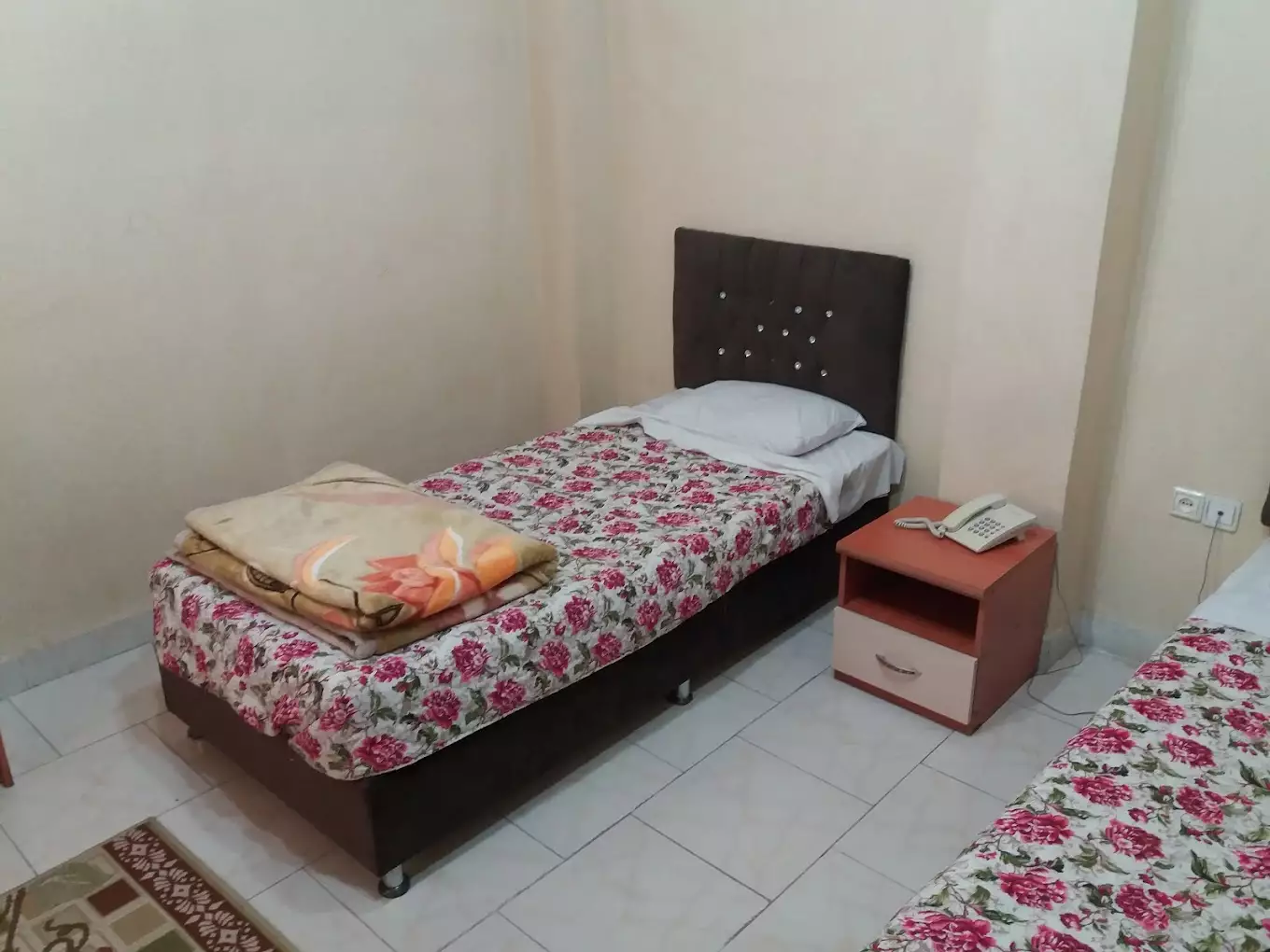 تخت یک‌نفره با روتختی گل‌دار در هتل سیروس