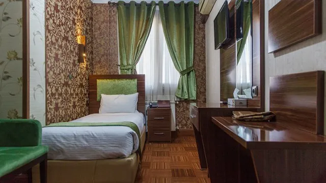 اتاق هتل شهریار با تخت یک‌نفره و پرده سبز