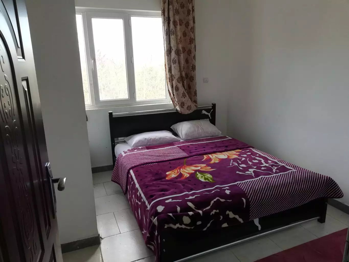 تخت دونفره با روتختی گلدار در هتل توکل