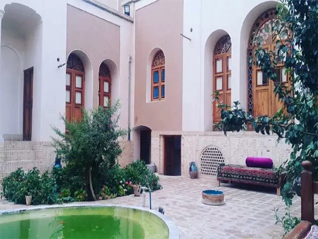 حیاط خانه مرشدی با حوض و پنجره‌های رنگی