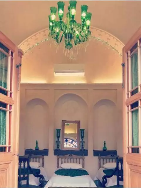 اتاق سنتی خانه مرشدی با لوستر سبز و تخت‌های چوبی