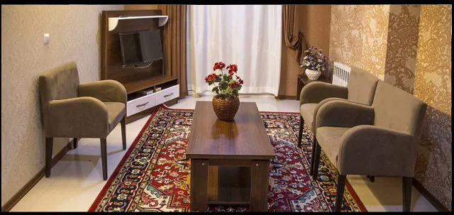 اتاق نشیمن هتل کوروش با مبل‌های کرم و فرش قرمز