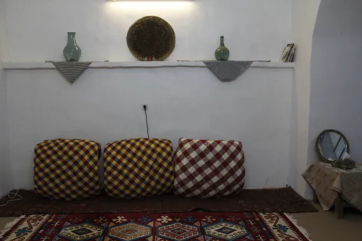 پشتی‌های چهارخانه و قالی در فضای نشیمن نارتی‌ تی