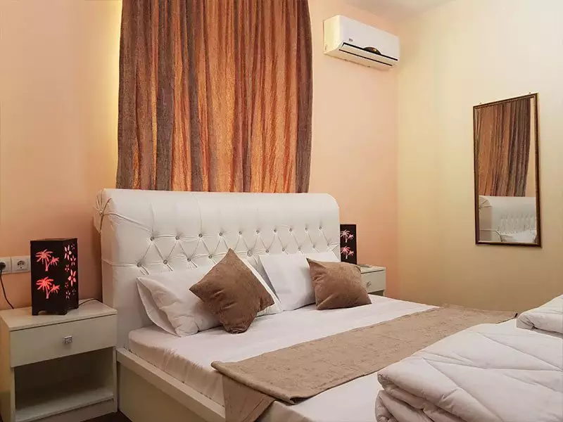تخت دونفره سفید در اتاق هتل نخل