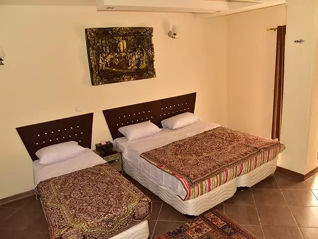 دو تخت یک‌نفره با روتختی طرح‌دار در هتل پلاس