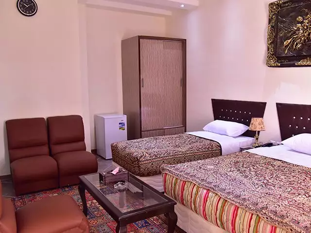 دو تخت یک‌نفره و کمد در اتاق هتل پلاس