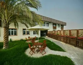 حیاط سرسبز هتل ریم رام با میز و صندلی
