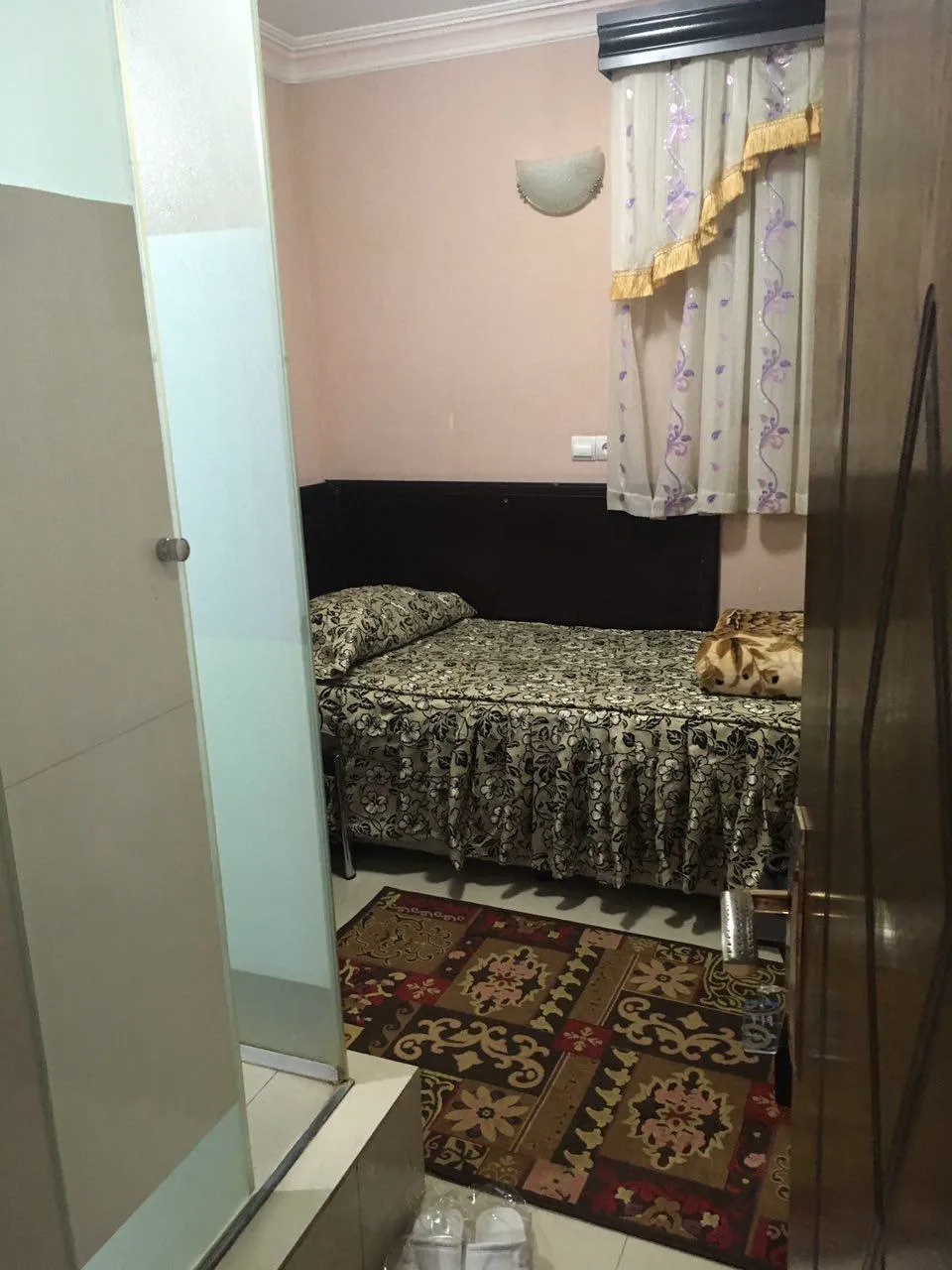 اتاق یک‌تخته هتل سعید با فرش طرح‌دار و پرده گل‌دار