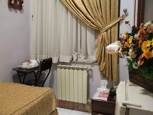 اتاق هتل مهر با پرده‌های طلایی و میز چای