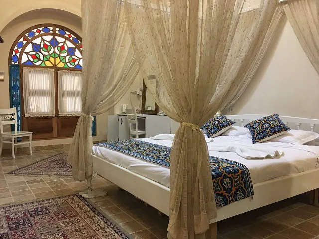 تخت خواب پرده‌دار و پنجره شیشه‌رنگی هتل آریانا
