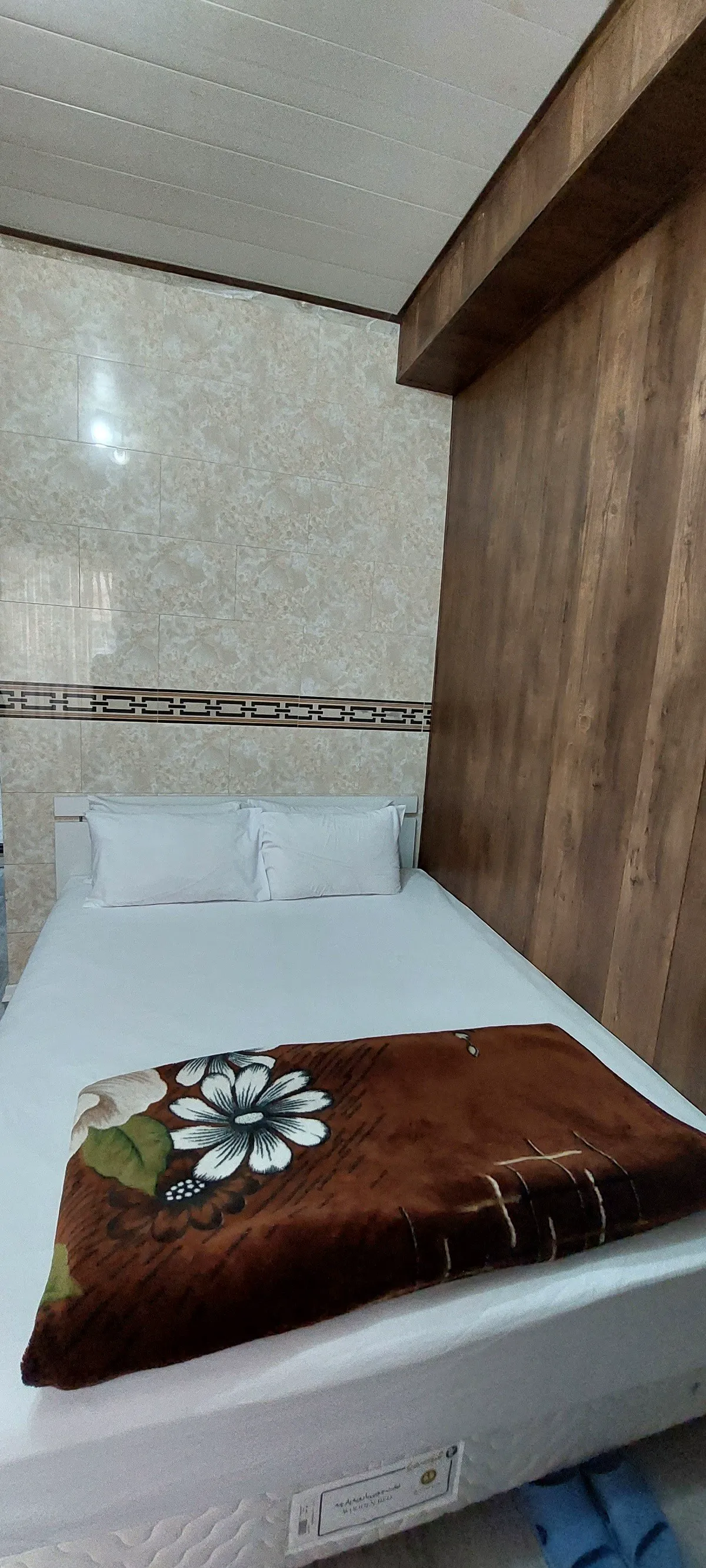 تخت یک‌نفره با پتوی گل‌دار در هتل خرم