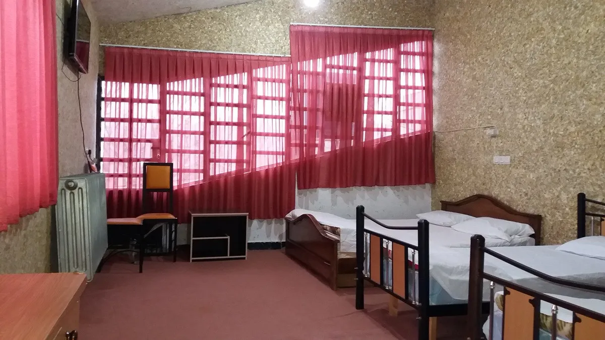 اتاق هتل قصر با تختهای یکنفره و پردههای قرمز