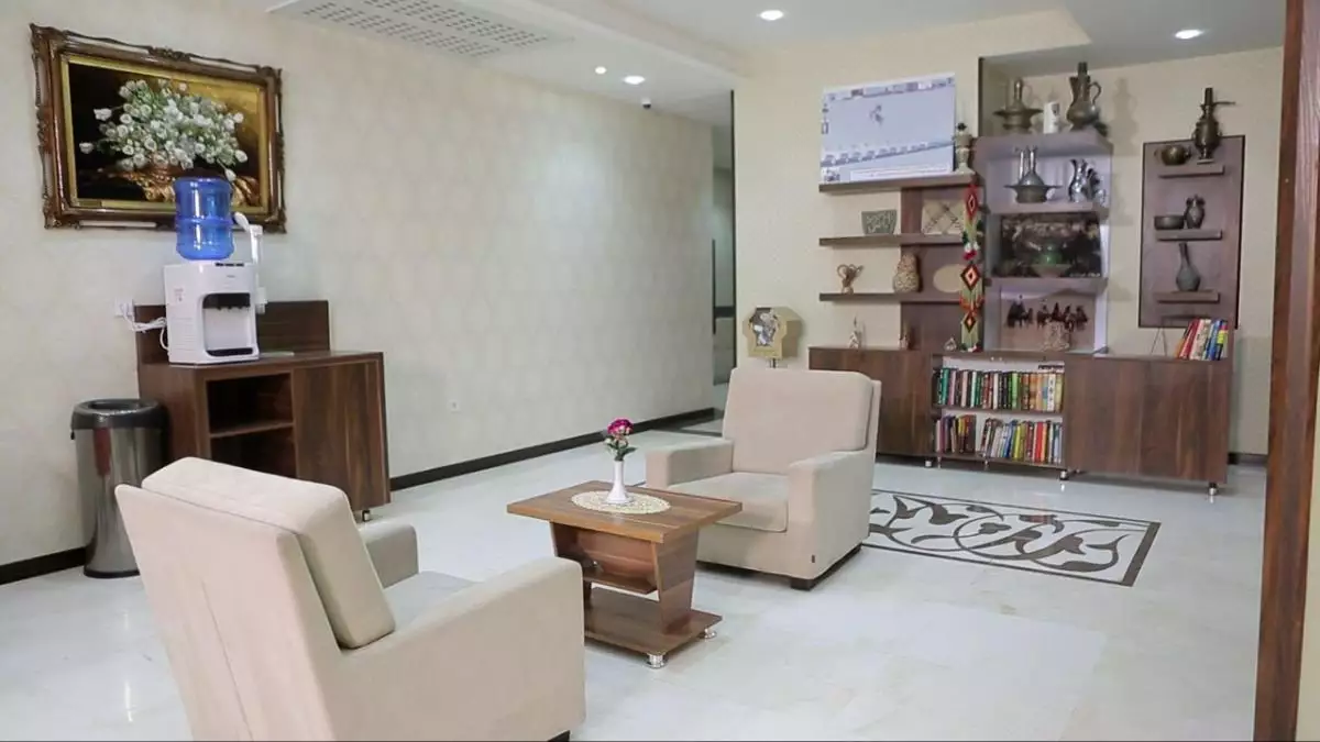 اتاق نشیمن هتل علمدار با مبل و قفسه کتاب