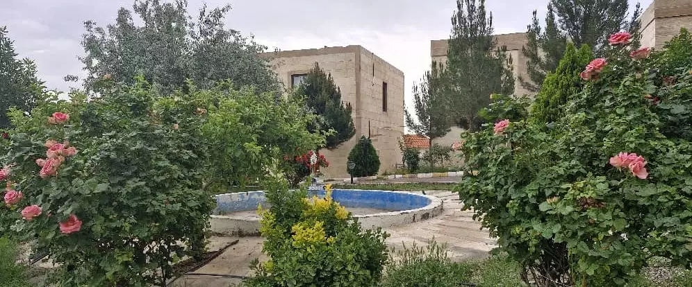 حیاط ویلاهای کوهستانی ارس با حوض و بوته‌های گل‌دار