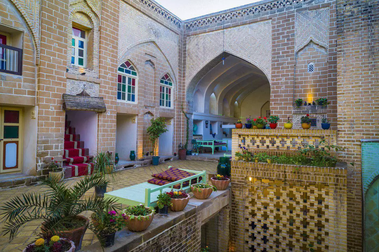 حیاط آجری هتل طبیب شوشتری با حوض و گلدان‌ها