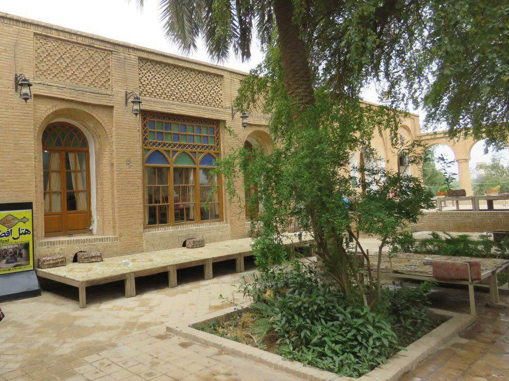 حیاط عمارت افضل با نمای آجری و درختان