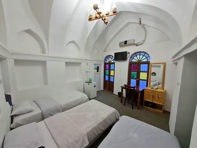 اتاق خواب عمارت افضل با پنجره‌های رنگی و سه تخت