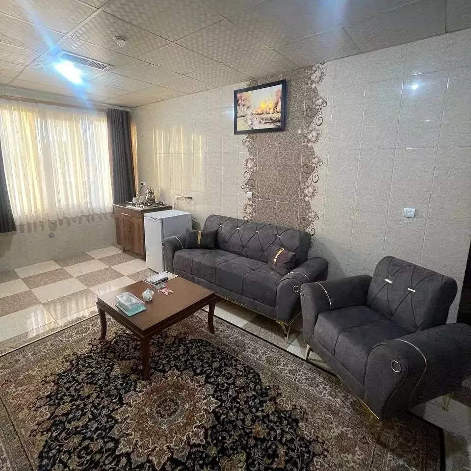 نشیمن هتل آسام با مبل‌های خاکستری و فرش ایرانی