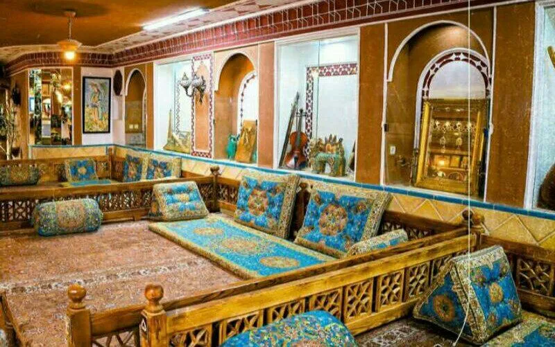 فضای نشیمن سنتی با پشتی‌های آبی و چوب‌کاری