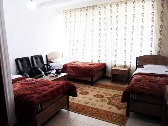 اتاق سهتخته هتل افشار با فرش و پردههای طرحدار