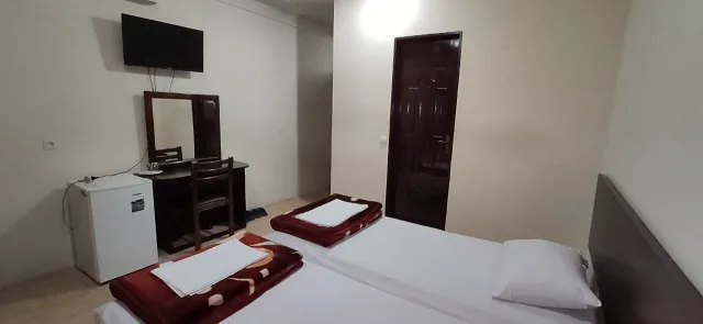 تخت دونفره و میز تلویزیون در اتاق هتل پردیسان