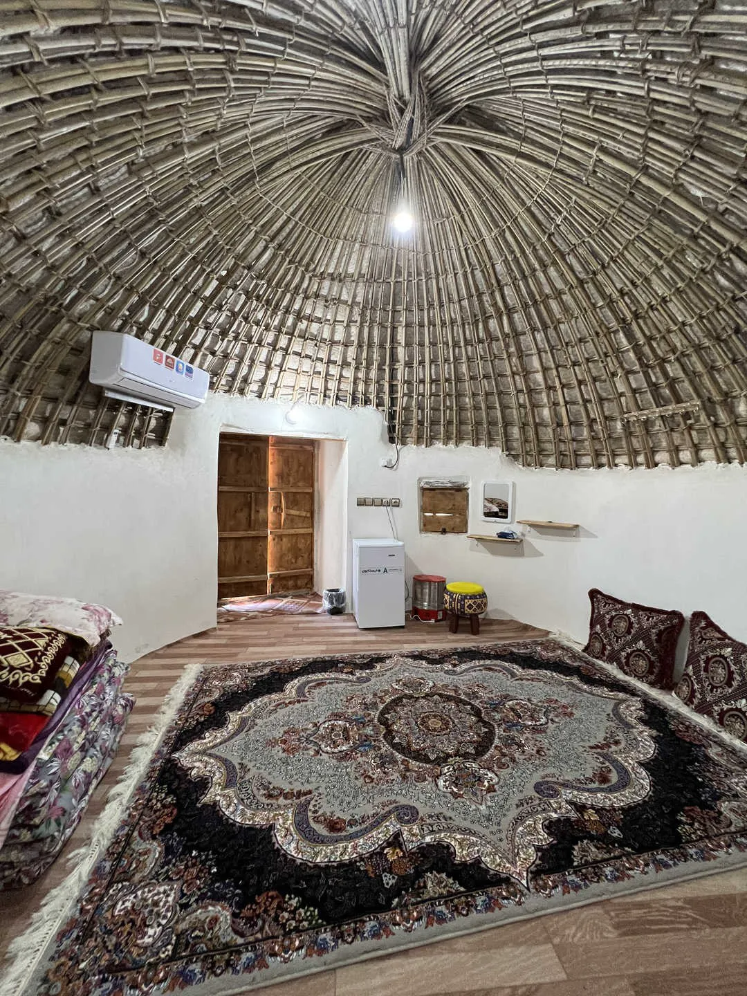 اتاق کلبه فردیس با سقف حصیری و فرش مرکزی