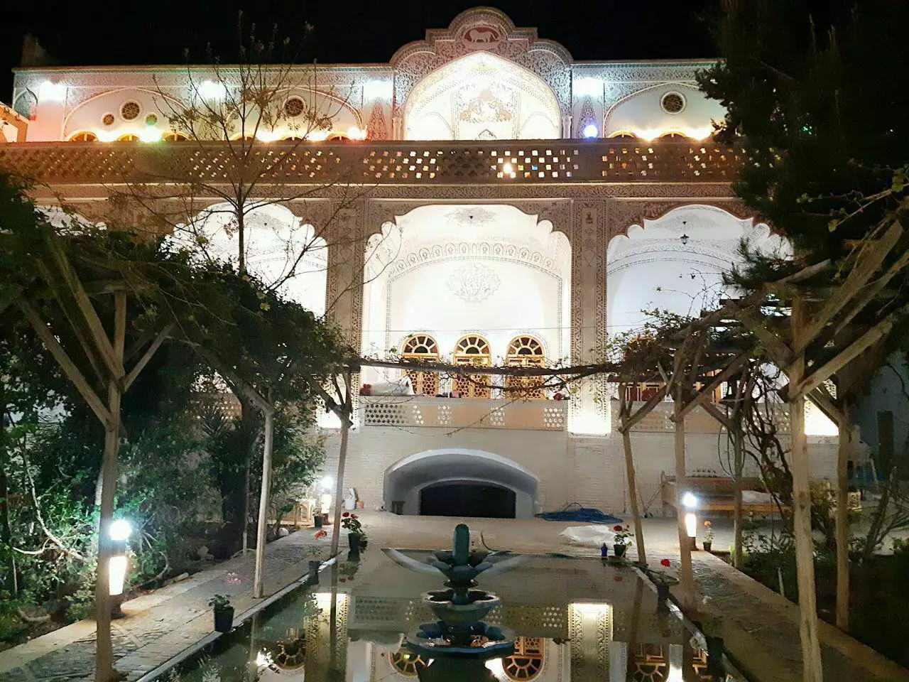 حیاط خادمی در شب با حوض و نمای روشن ساختمان