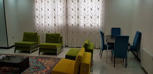 نشیمن با مبل‌های سبز و میز غذاخوری هتل سروناز