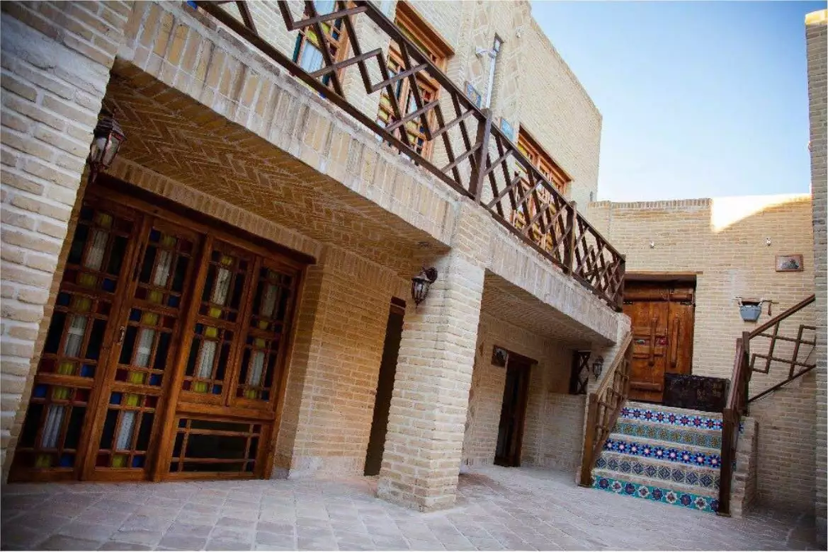 نمای حیاط ددمان با ایوان آجری و پلکان کاشی‌کاری‌شده