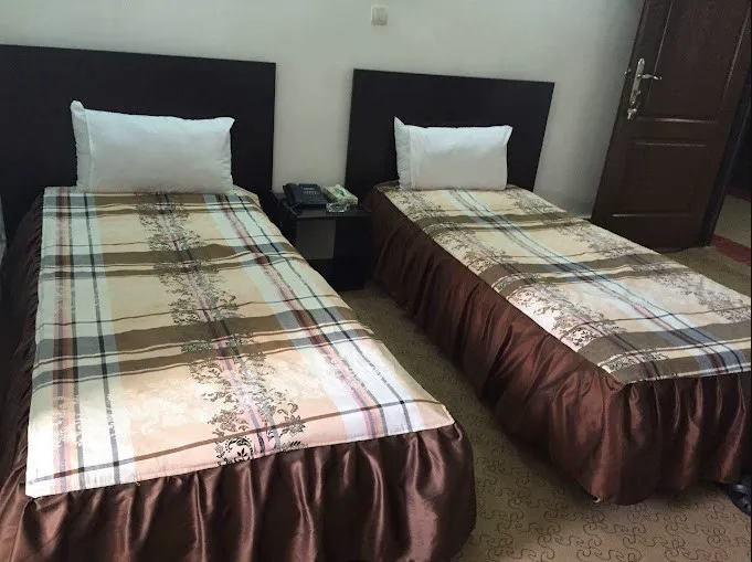 دو تخت یک‌نفره با روتختی چهارخانه در هتل نگین