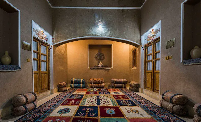 اتاق نشیمن اقامتگاه انار با فرش و پشتی‌های سنتی