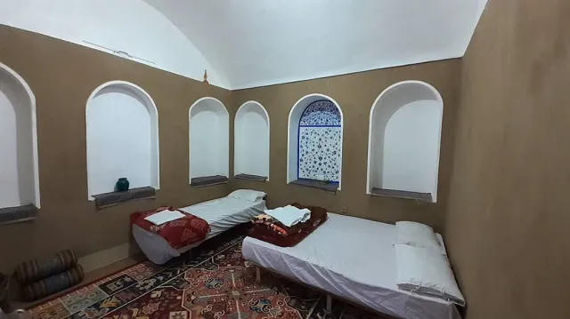 اتاق اقامتگاه انار با دو تخت و طاقچه‌های قوسی