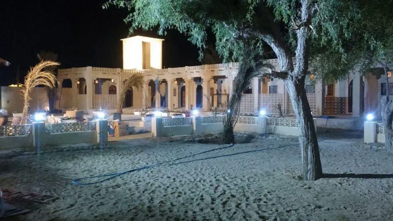 نمای شبانه حیاط خانه دوست با درختان و چراغ‌ها