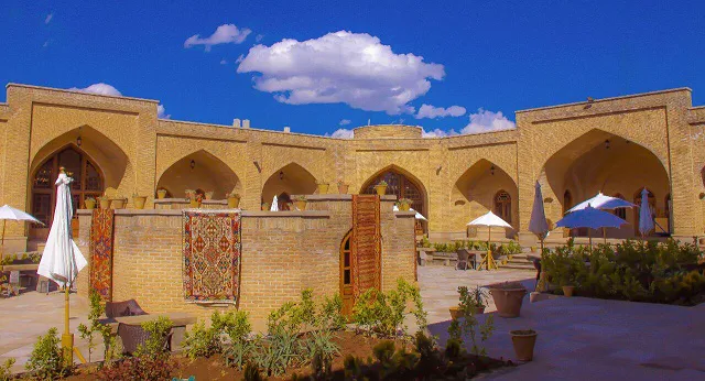 حیاط کاروانسرای یام با ایوانهای آجری و گلدانها
