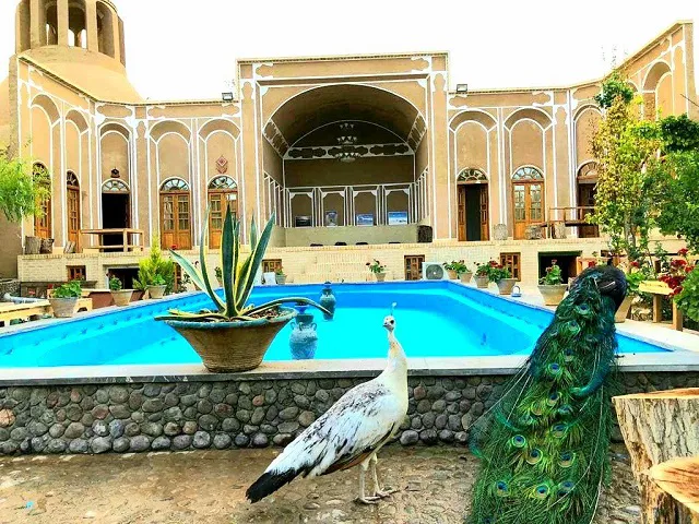 حیاط سرای جهانگرد با حوض آبی و طاووس