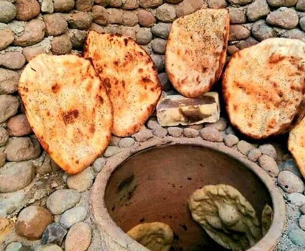 نانهای تنوری کنار تنور سنگی در سرای جهانگرد