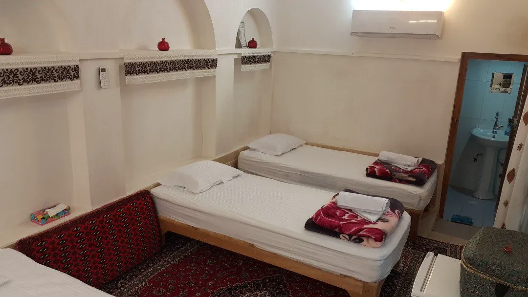 اتاق سرای جهانگرد با تختهای یکنفره و رختخواب سنتی