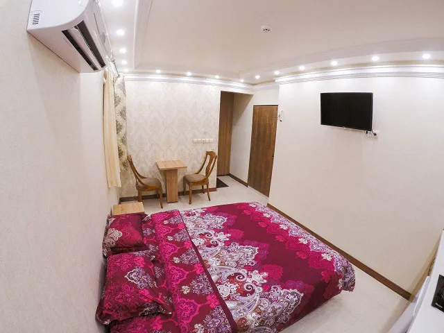 تخت دونفره با روتختی گل‌دار در اتاق هتل شیرین